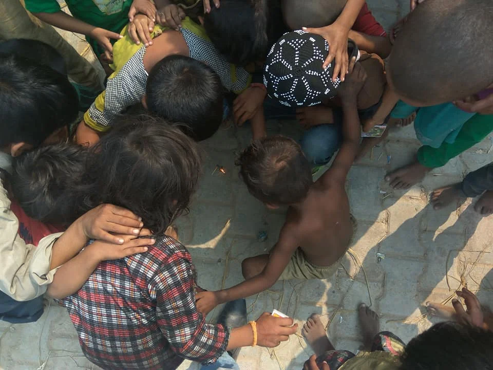 Children gathered around on the ground.