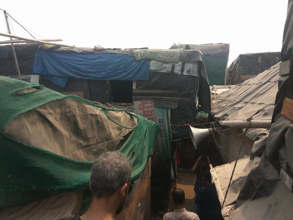 Informal settlement alley with makeshift tarpaulin shelters.