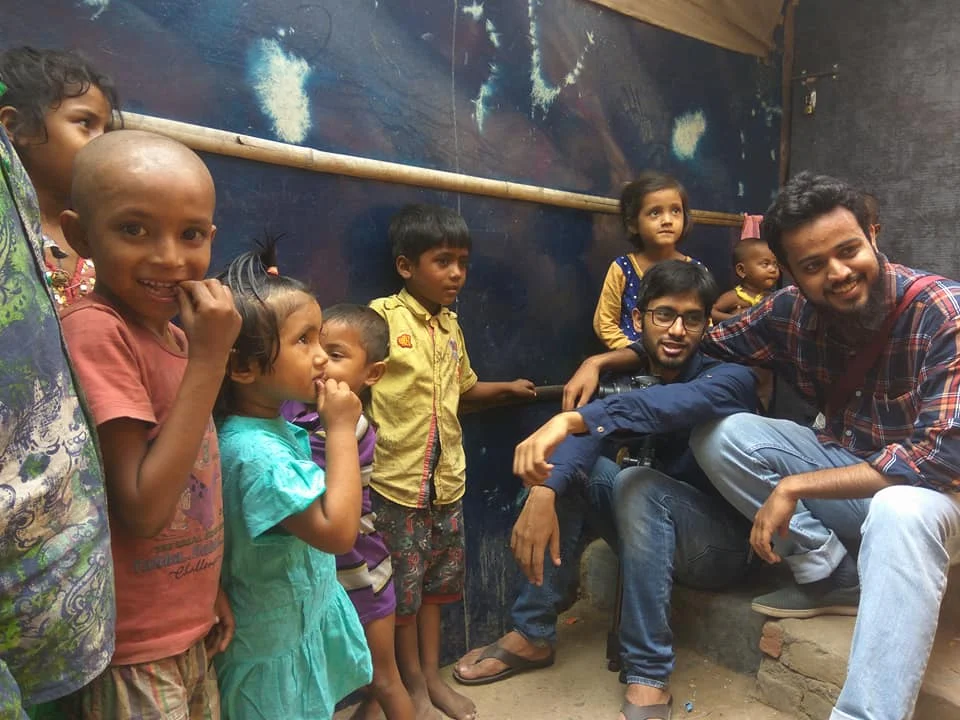 Group of children with two men smiling outdoors.