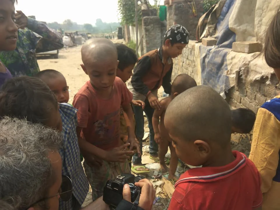 Children gathered around camera outdoors.