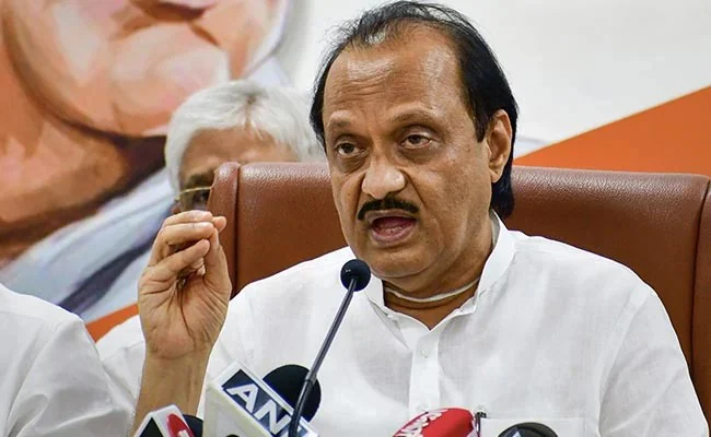 Man speaking at a press conference with microphones.