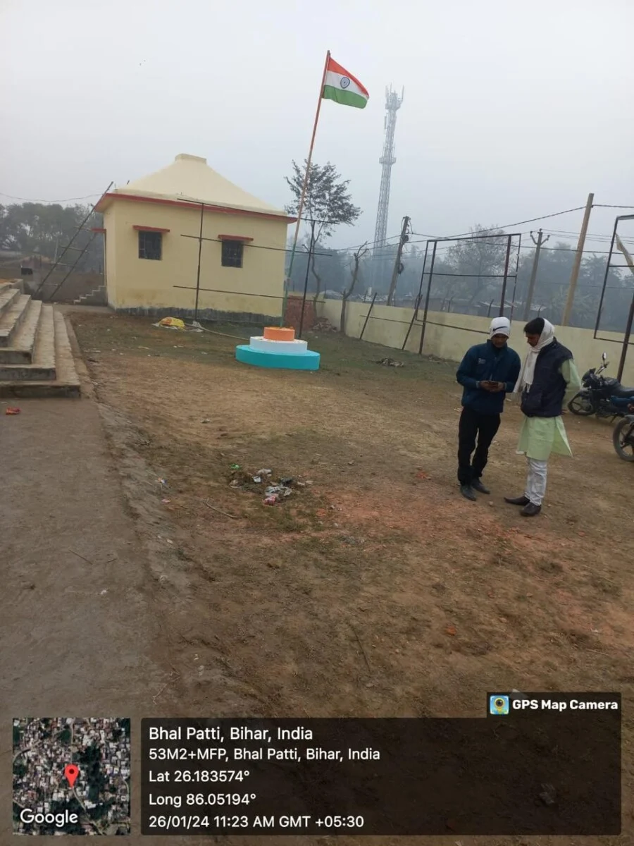 Two people near building with Indian flag in Bihar.