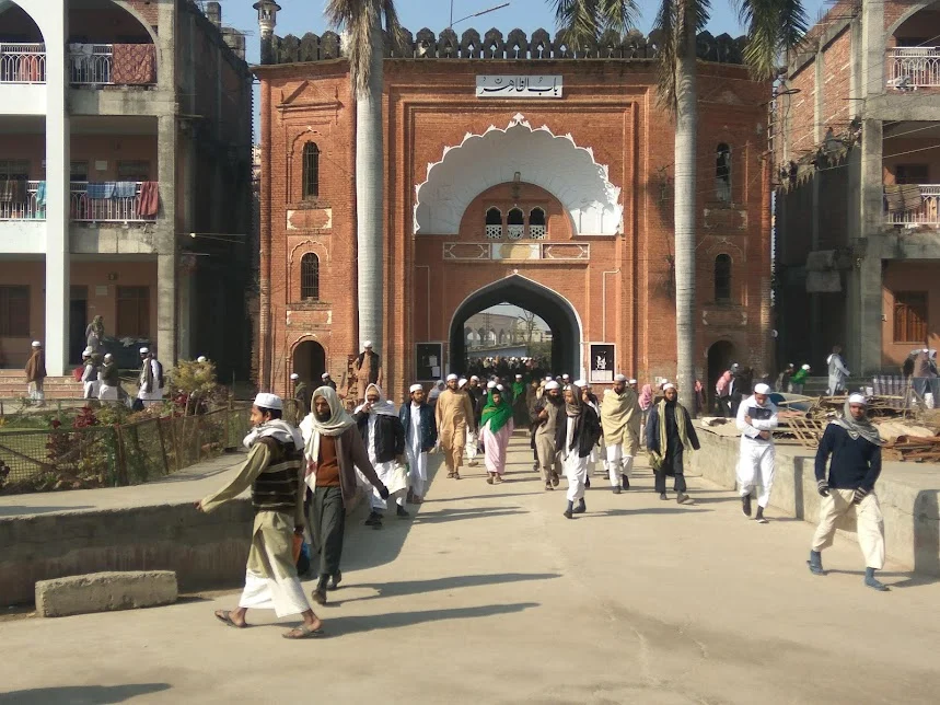 People exiting traditional brick archway of mosque.