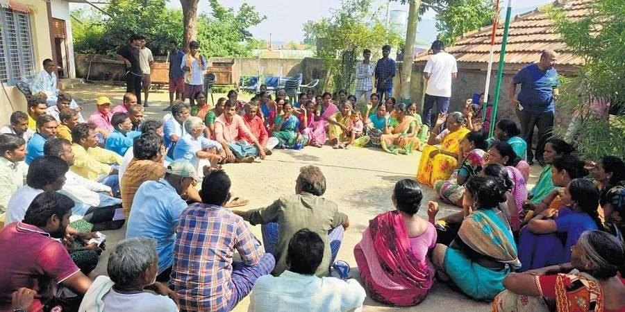 Community meeting outdoors in village setting.