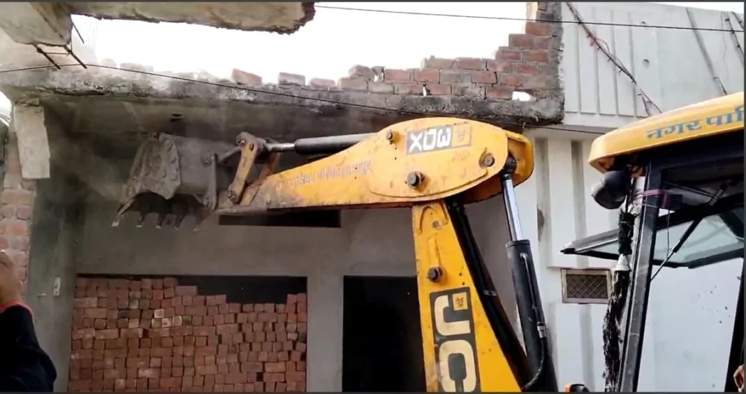 Excavator demolishing brick building facade.