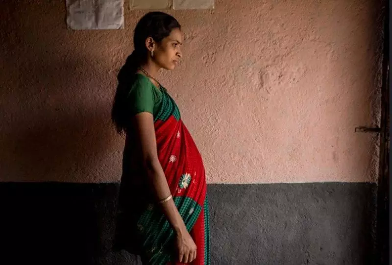 Pregnant woman in traditional saree looking thoughtful.