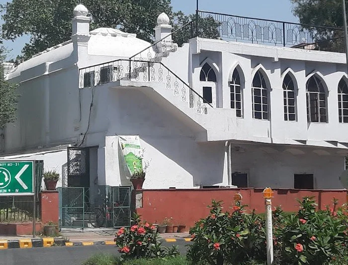 White historical building with arched windows and greenery.