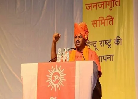 Man speaking at podium with cultural symbols.