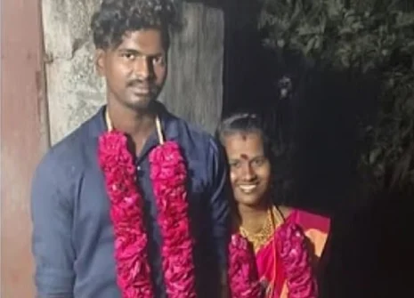 Couple wearing garlands and smiling at night.